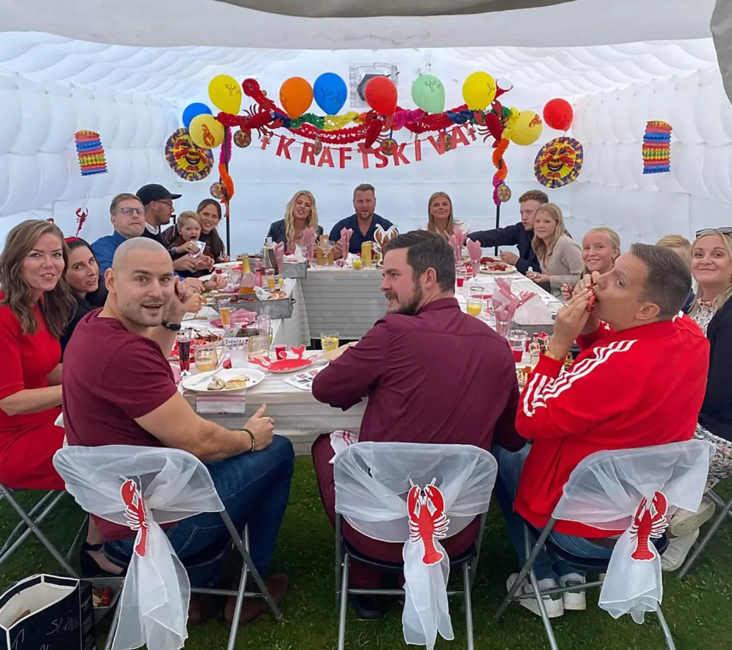 Gäster vid dukade bord i ett vitt uppblåsbart partytält med ballonger och kräftdekorationer